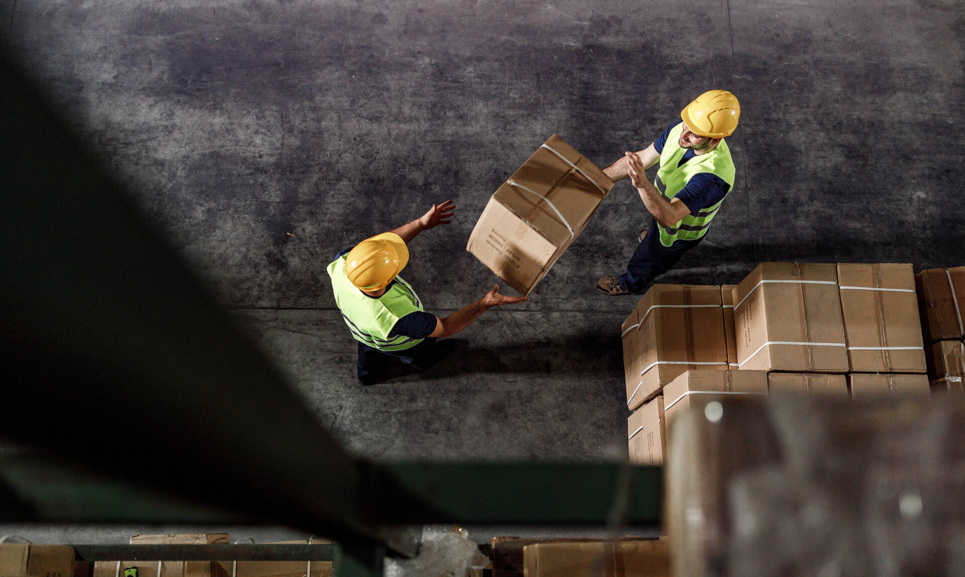 Above view of manual workers working with cardboard boxes in distribution warehouse.